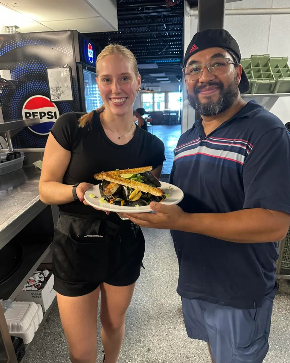 High Tide server and cook holding a plate of mussels